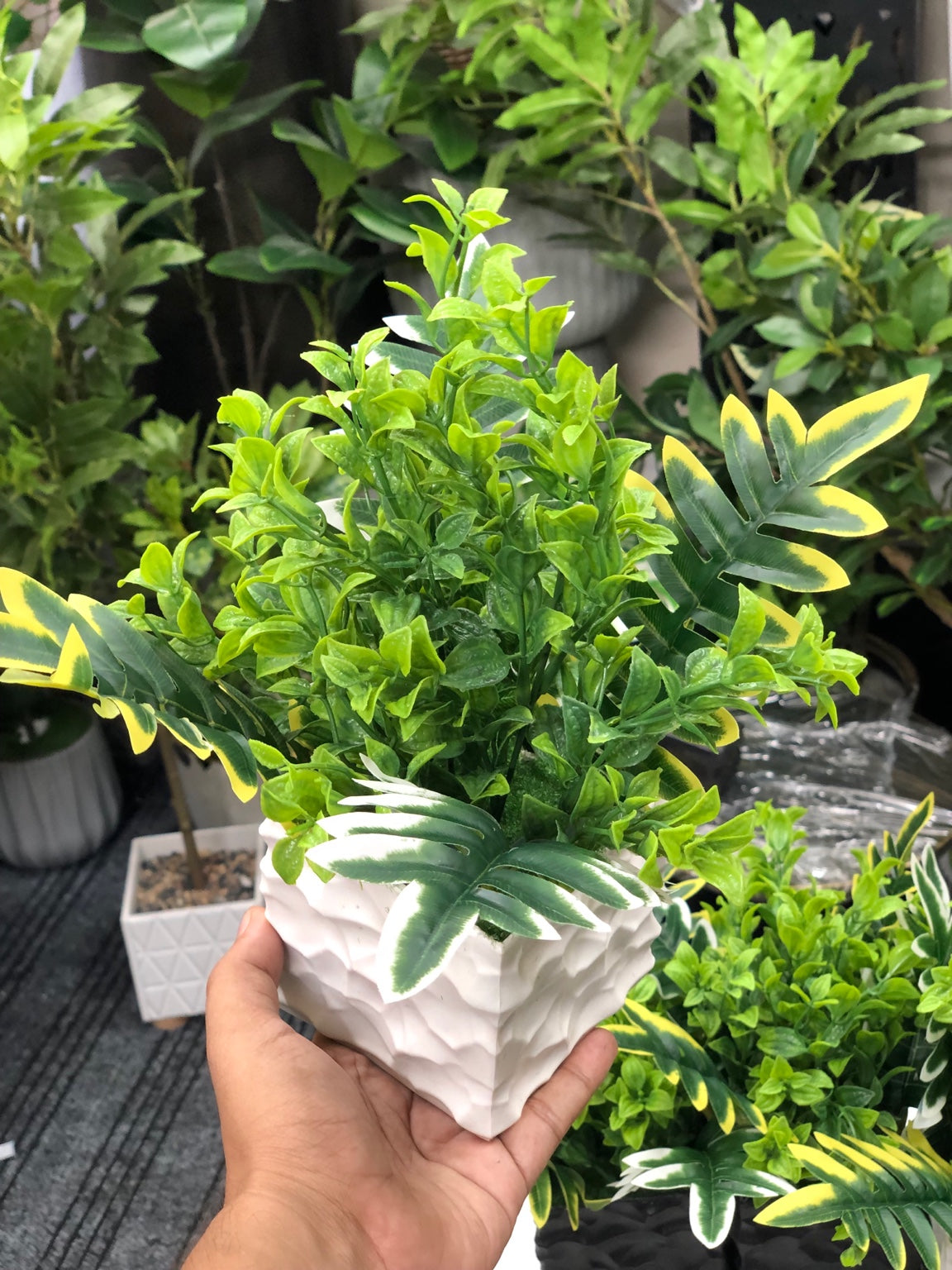 Artificial mixed green foliage arrangement in modern white textured pot