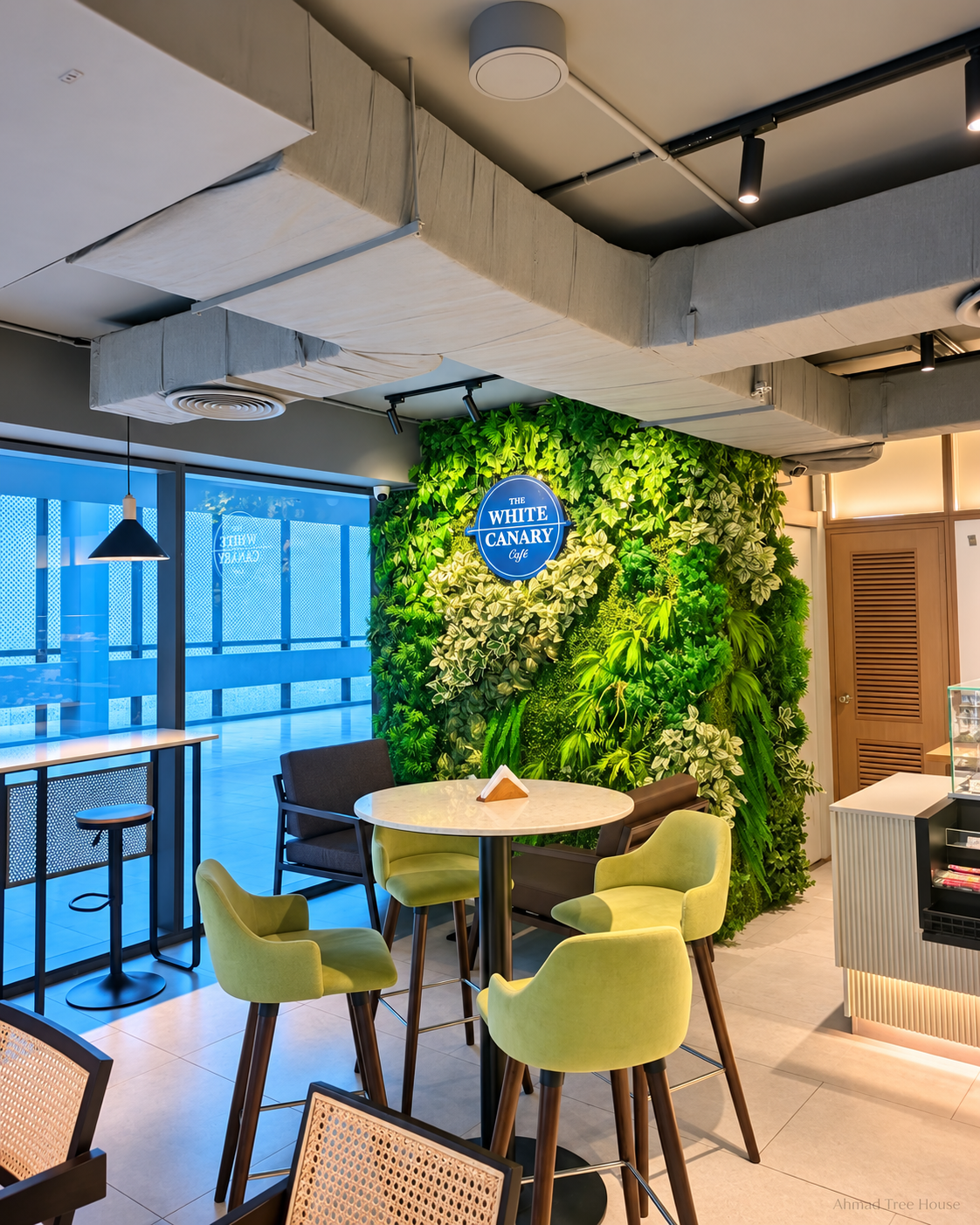 The White Canary Café corner seating beside a green wall — Ahmad Tree House project