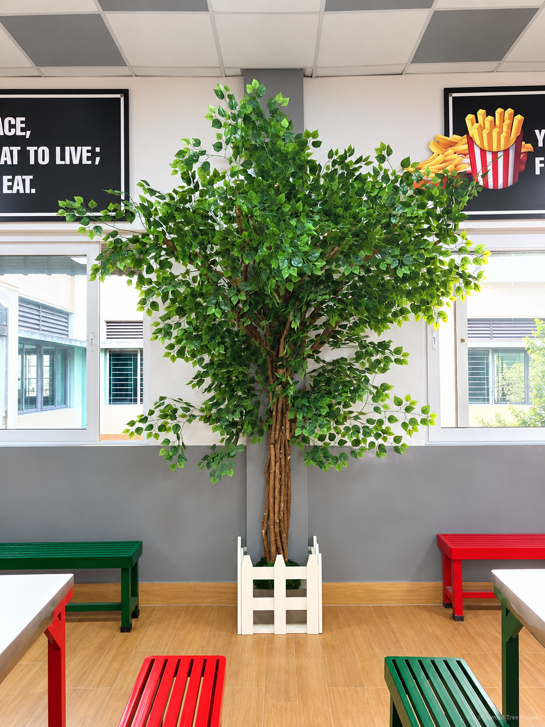 Green statement tree beside colourful restaurant benches — Ahmad Tree House project
